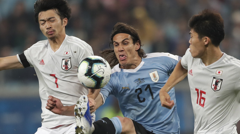 Cīņa par bumbu mačā starp Urugvajas un Japānas izlasēm. Foto: AP/Scanpix